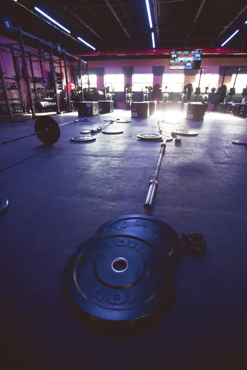 Barre et disques posés au sol dans une salle vide
