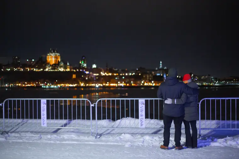 Couple accoudé à la rambarde devant la ville illuminée