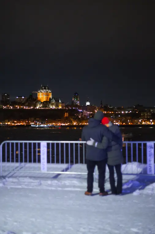 Silhouettes devant le fleuve gelé et la ville de nuit