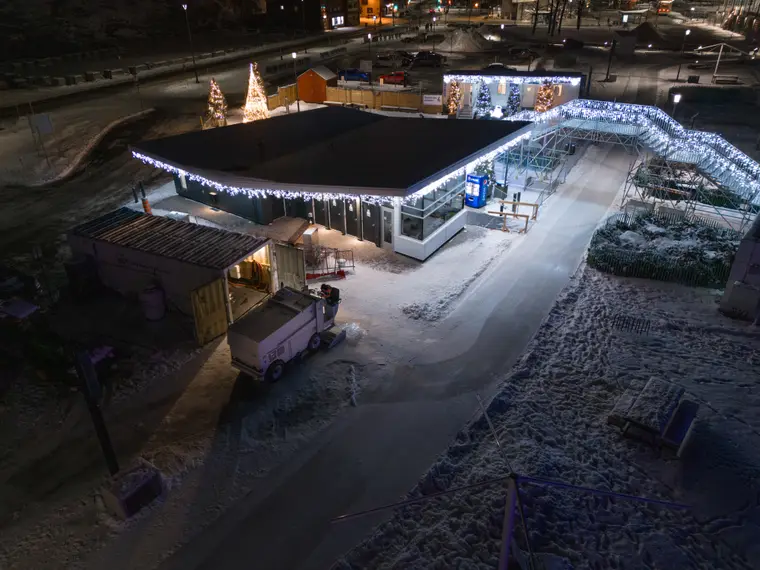 Bâtiment illuminé et patinoire vus du ciel, le soir