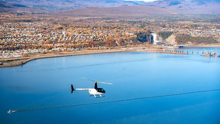 Hélicoptère survolant un lac devant une ville
