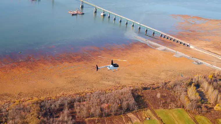 Hélicoptère survolant les battures près d’un pont